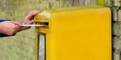 Brief wird in Briefkasten eingeworfen.